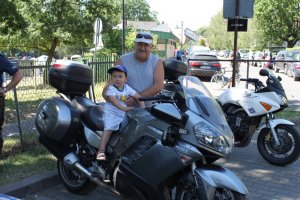 mężczyzna trzymający dziecko, które siedzi na policyjnym motocyklu