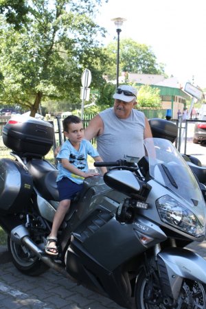 mężczyzna trzymający dziecko, które siedzi na policyjnym motocyklu