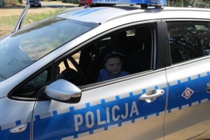 chłopiec siedzi za kierownicą policyjnego radiowozu