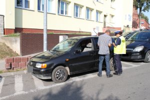 Policjantka wykonuje czynności służbowe wobec kierującego czarnym Volkswagenem Polo