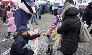 policjantka wraz z maskotką policyjną wręczają odblask dziecku