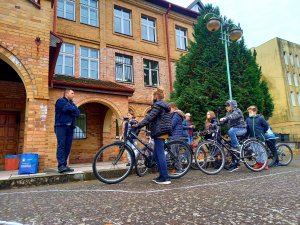 Boisko szkolne, uczniowie szkoły jeżdżący na rowerze, z Policjantem
