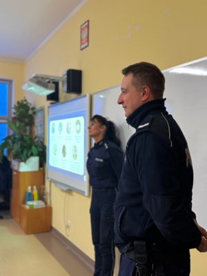 policjant i policjantka w umundurowaniu stoją w klasie
