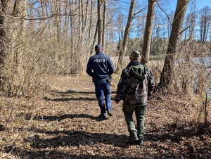 Funkcjonariusz Policji wspólnie z funkcjonariuszem Straży Rybackiej idący linią brzegową